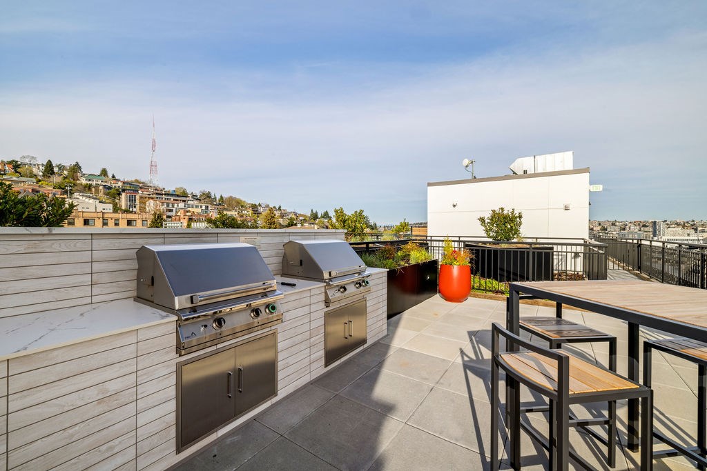 A rooftop patio with barbecue grills and seating.