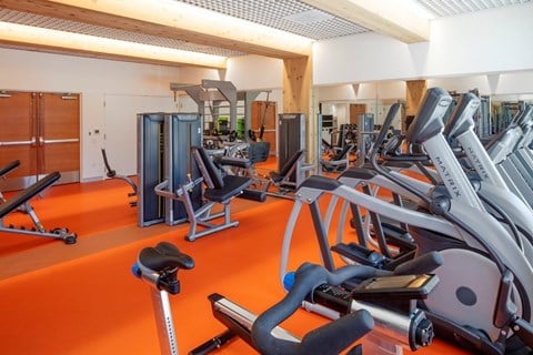 A gym with orange flooring and various exercise equipment.