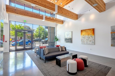A modern living room with a couch, ottoman, and artwork on the wall.