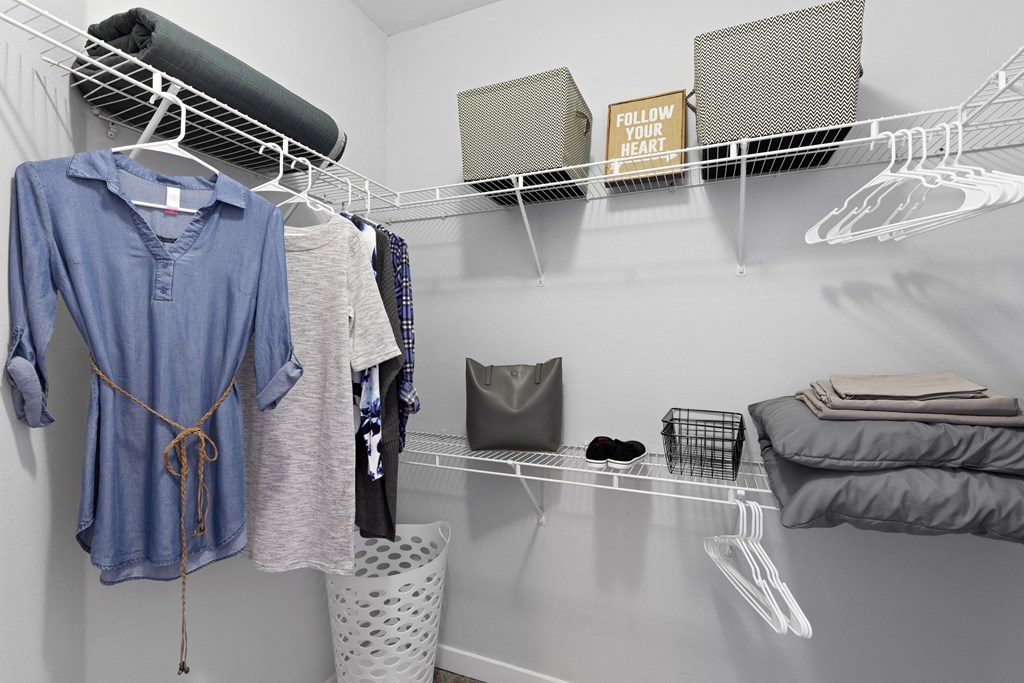 a walk in closet with a rack of clothes and a bed in it