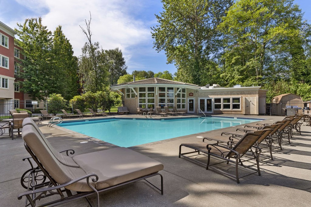 a swimming pool with chaise lounge chairs and a building in the background