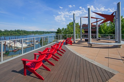 A row of red chairs are lined up on a wooden deck.