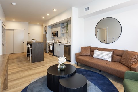A modern living room with a brown couch and a round mirror on the wall.