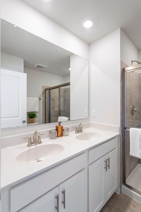 A white bathroom with a double sink and a mirror.