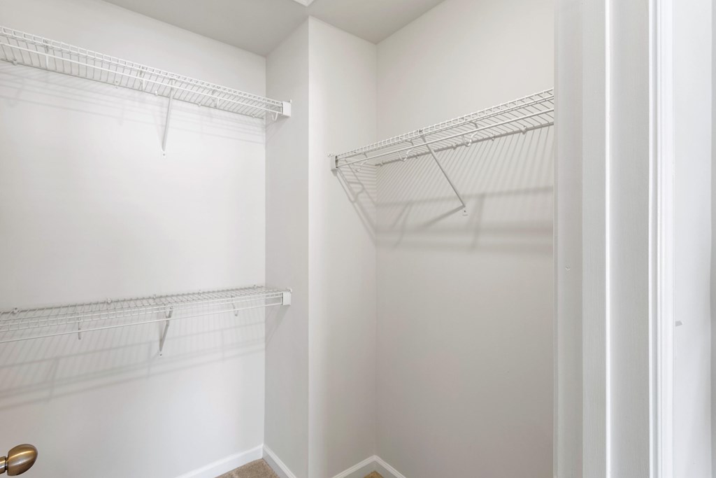 A white closet with two shelves and a door.