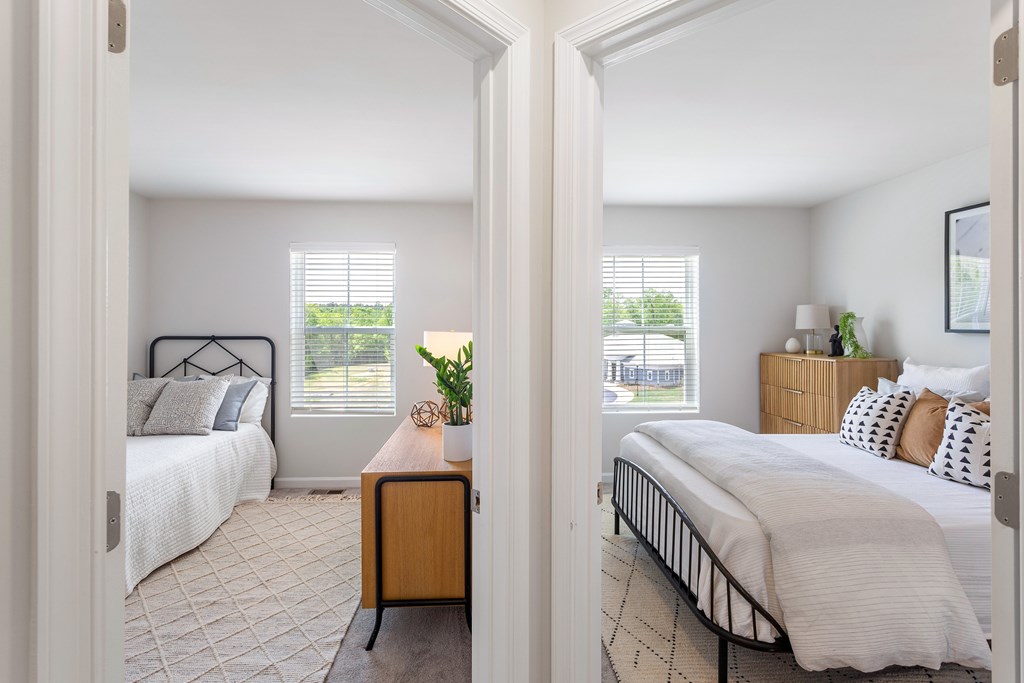 A bedroom with a bed, nightstand, and window with blinds.