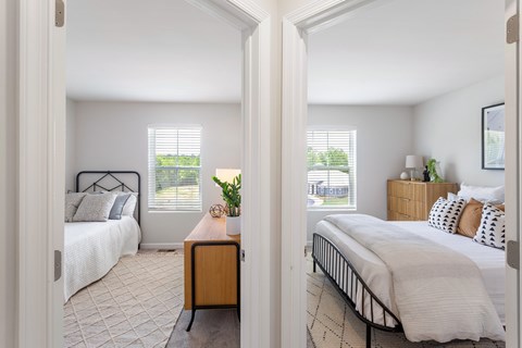 A bedroom with a bed, nightstand, and window with blinds.