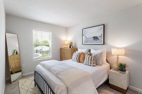 A bedroom with a large bed, a nightstand with a lamp, and a framed picture of a bear on the wall.