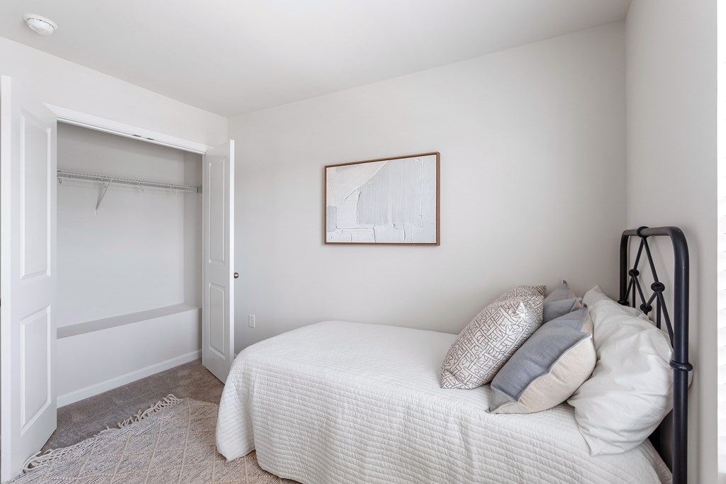 A bedroom with a white bed and a framed picture on the wall.