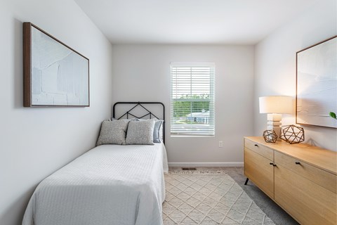 A bedroom with a bed, nightstand, and a painting on the wall.