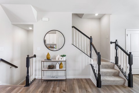 A staircase with a round mirror above it.