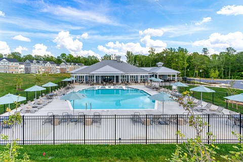 A large swimming pool surrounded by a black fence and a pavilion with a grey roof.