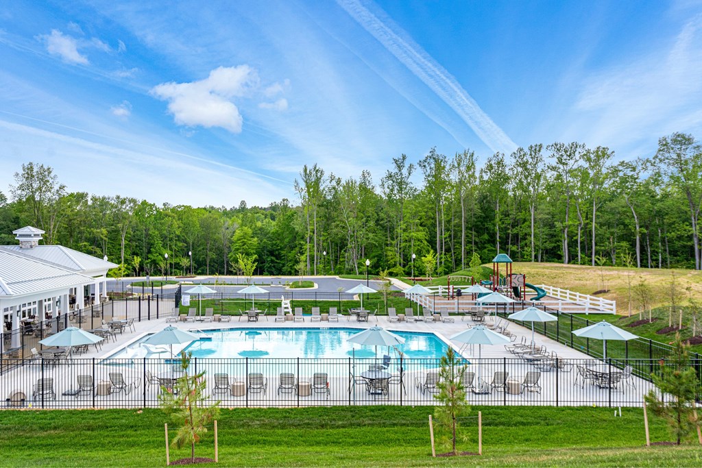 A large outdoor swimming pool surrounded by a fence and trees.
