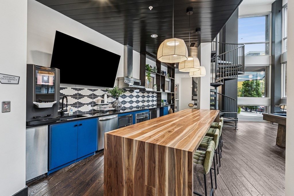 A modern kitchen with a long wooden island in the middle.