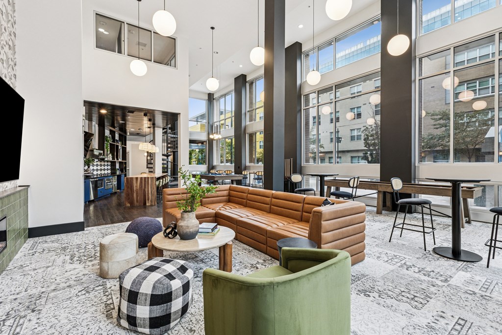 A modern living room with a green armchair, a wooden bench, and a black and white checkered ottoman.
