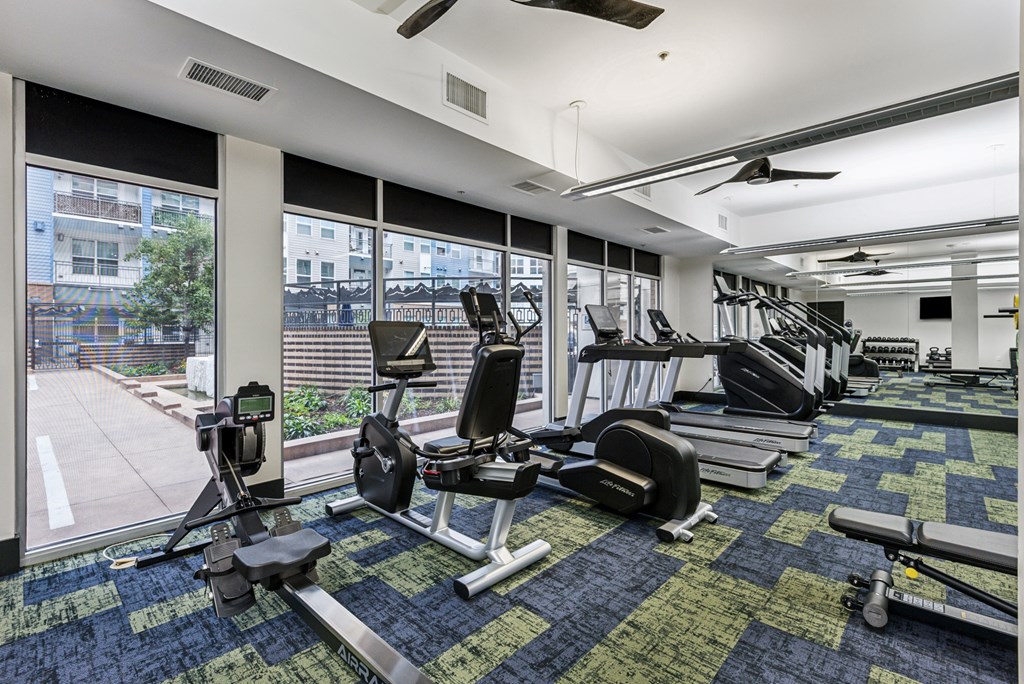 A gym with a variety of equipment including treadmills, weights, and exercise machines.
