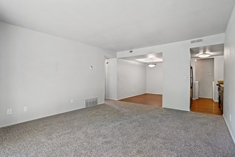 A spacious room with a carpeted floor and white walls.
