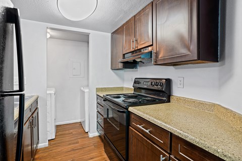 A kitchen with a black fridge and stove top oven.