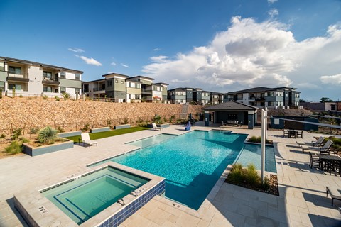 A swimming pool surrounded by a stone wall and chairs.