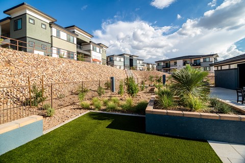 A modern house with a green lawn and a stone wall.