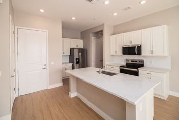 A kitchen with white cabinets and a white island.