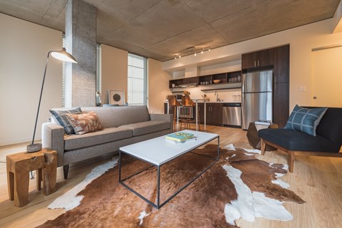 A modern living room with a grey couch, a white coffee table, and a brown cowhide rug.