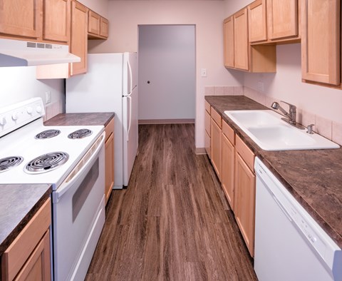 A kitchen with white appliances and wooden cabinets.