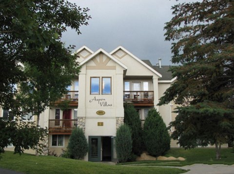 the front view of an apartment building with trees