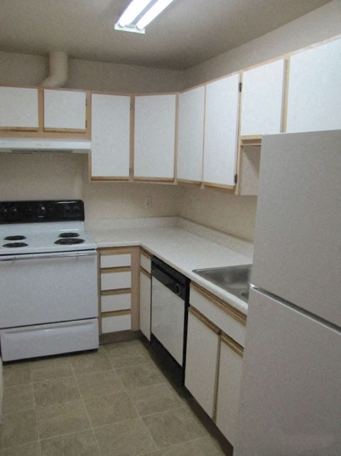 an empty kitchen with white appliances and white cabinets