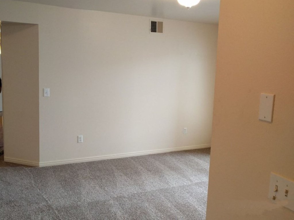 a living room with white walls and a carpeted floor