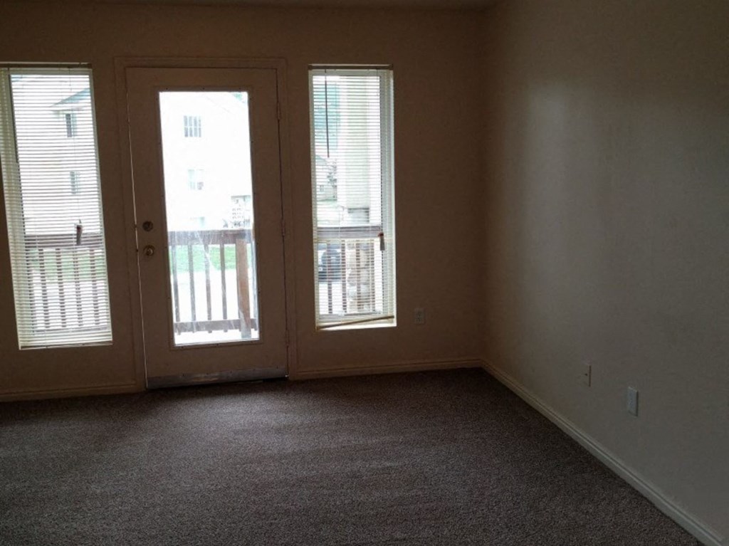 an empty living room with a door and window