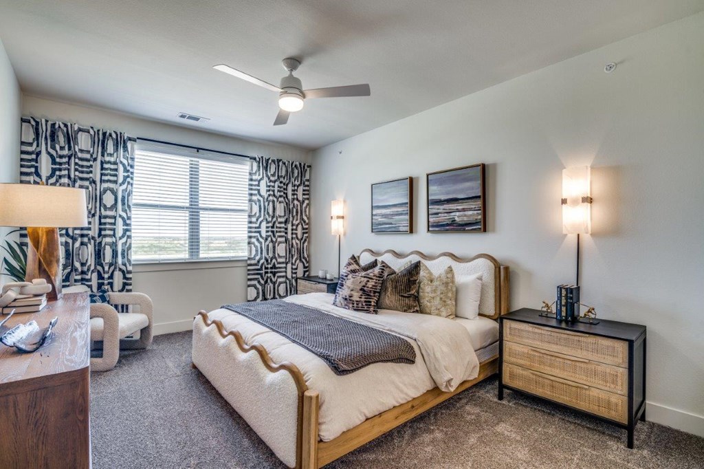 A bedroom with a large bed, a nightstand, and a ceiling fan.