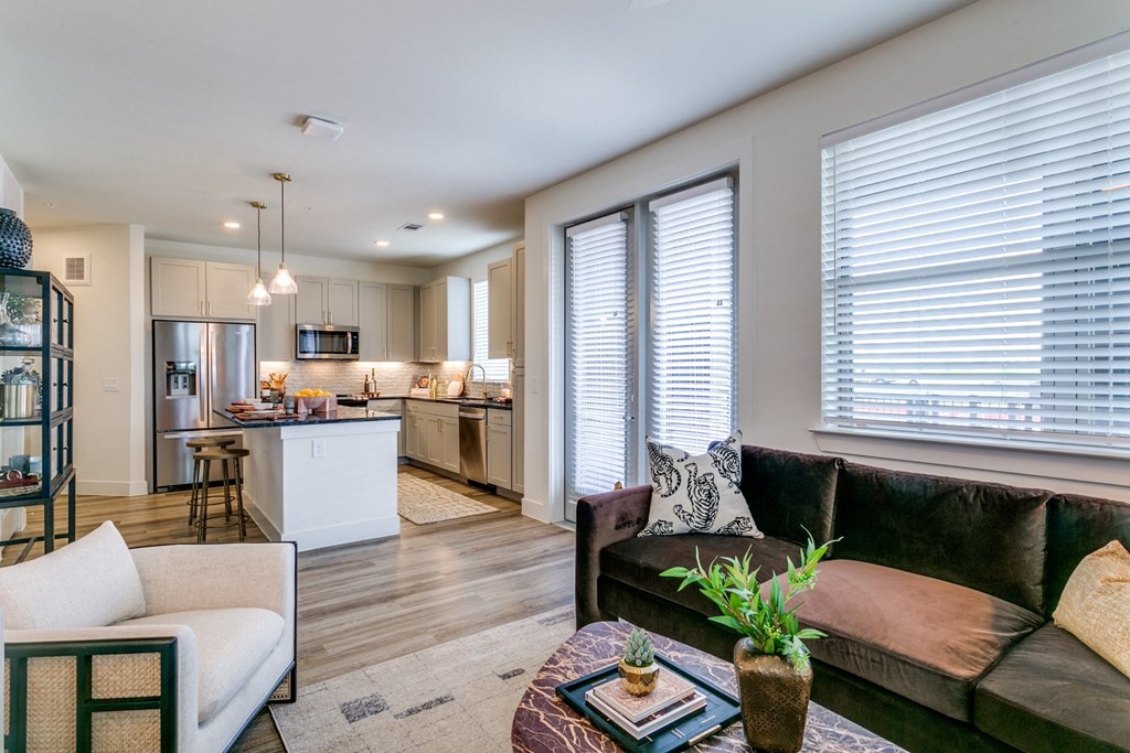 a living room with a couch and a table in front of a kitchen