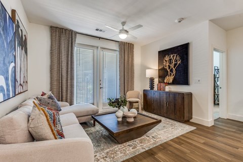 A living room with a beige couch, a coffee table, and a painting on the wall.