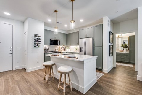 A kitchen with a white island and wooden bar stools.