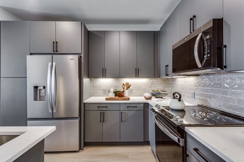 A modern kitchen with a stainless steel refrigerator and a white countertop.