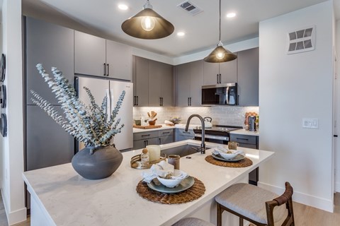 A modern kitchen with a marble countertop and a dining table set for two.