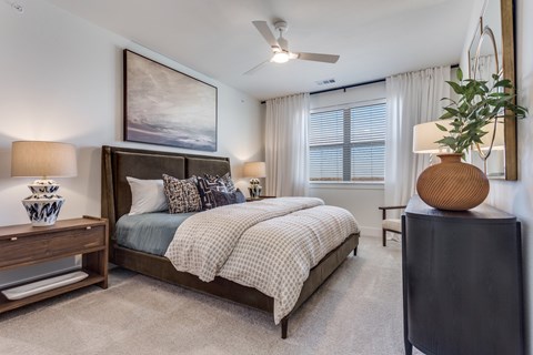 A bedroom with a large bed and a ceiling fan.
