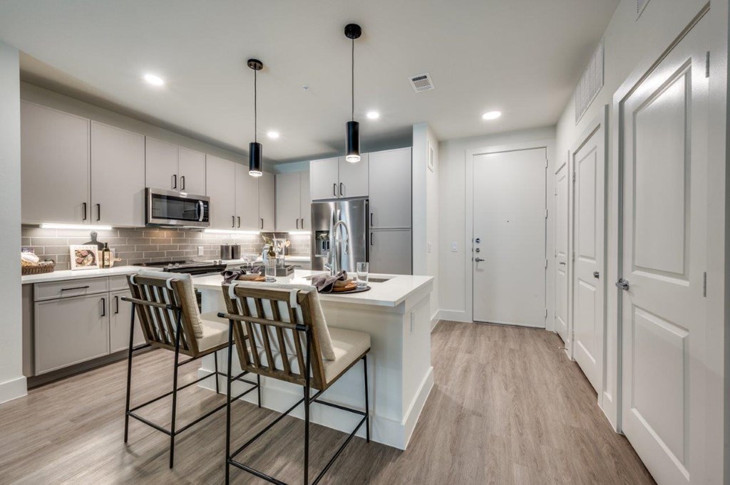 A kitchen with a white counter and brown chairs.
