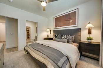 A bedroom with a large bed and a painting above it.