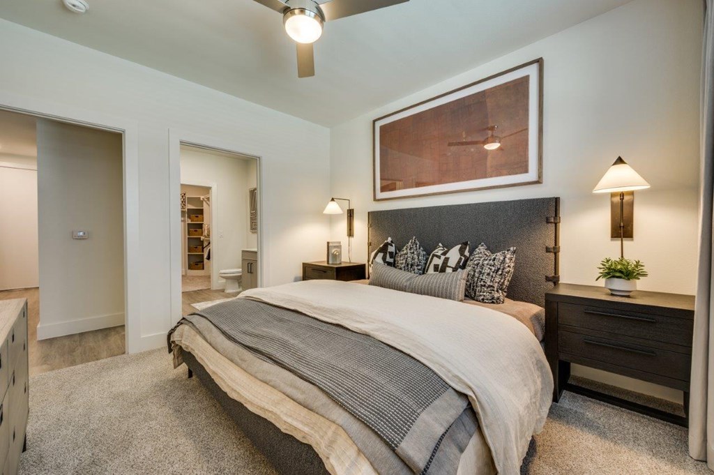 A bedroom with a large bed and a painting above it.