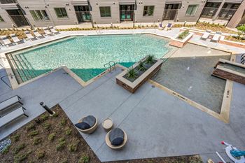 A pool surrounded by a concrete floor and a green lawn.