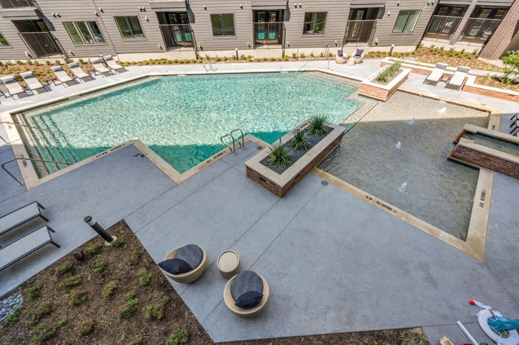 A pool surrounded by a concrete patio and a green lawn.
