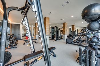 A gym with a variety of equipment including treadmills, weights, and exercise balls.