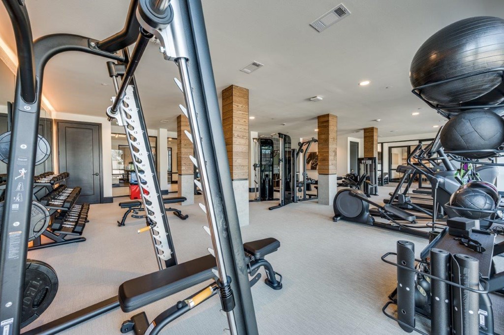 A gym with a variety of equipment including treadmills, weights, and exercise balls.