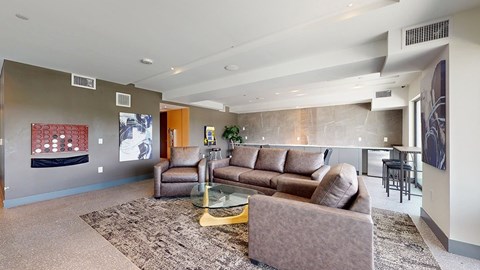 A living room with a brown couch and a glass coffee table.