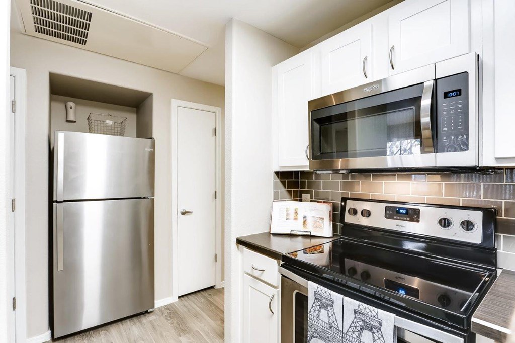 A kitchen with a stainless steel refrigerator, microwave, and oven.