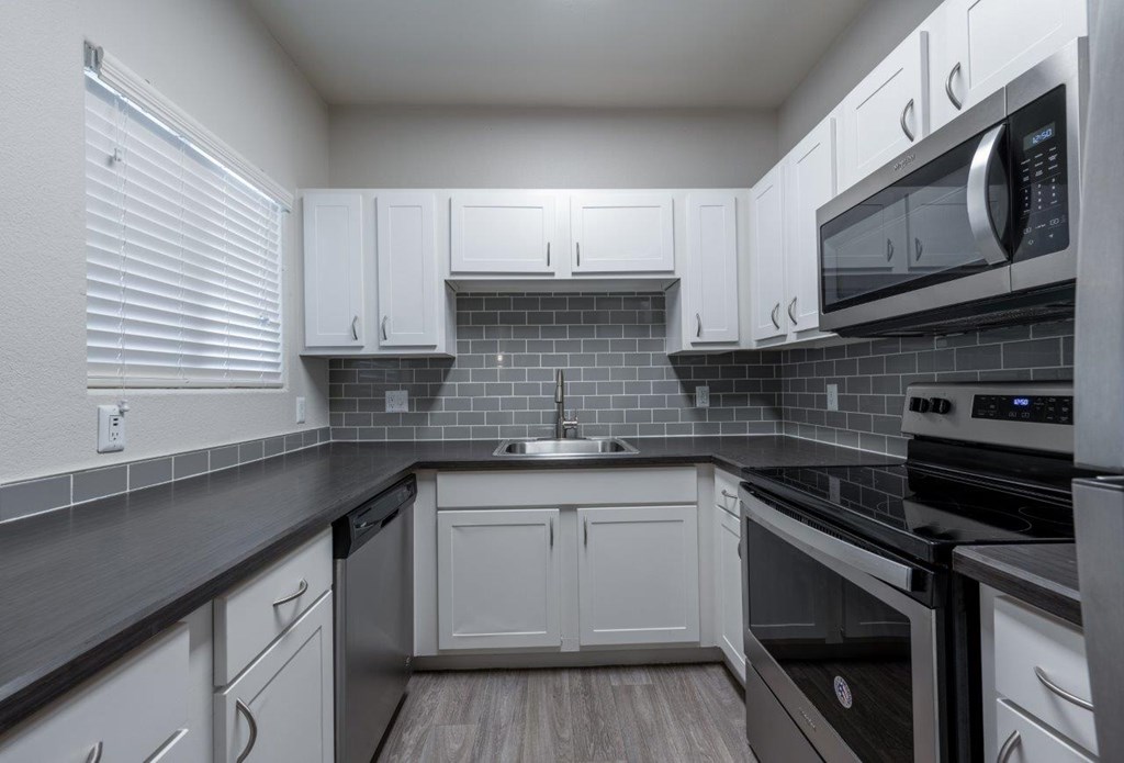 A kitchen with white cabinets and black countertops.