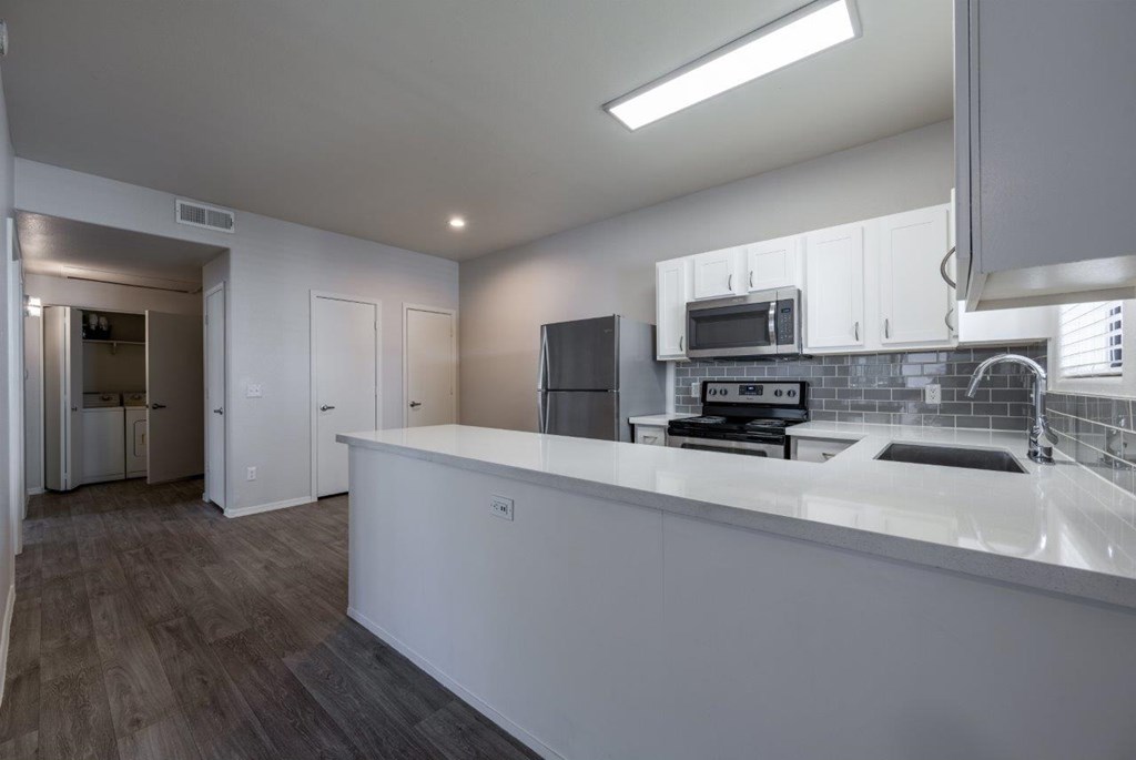 A modern kitchen with a white countertop and a microwave above it.