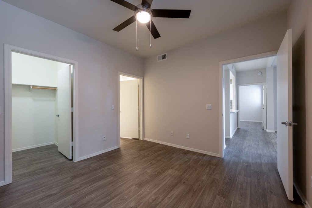 A room with a ceiling fan and wooden flooring.